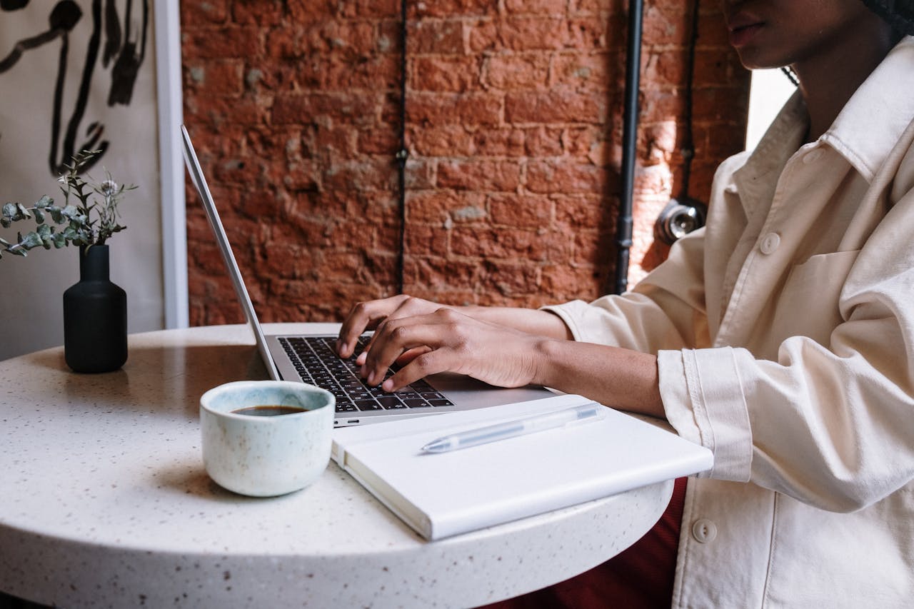 our-services-3 Woman working on a laptop with coffee in a cozy café, highlighting a productive and modern vibe.